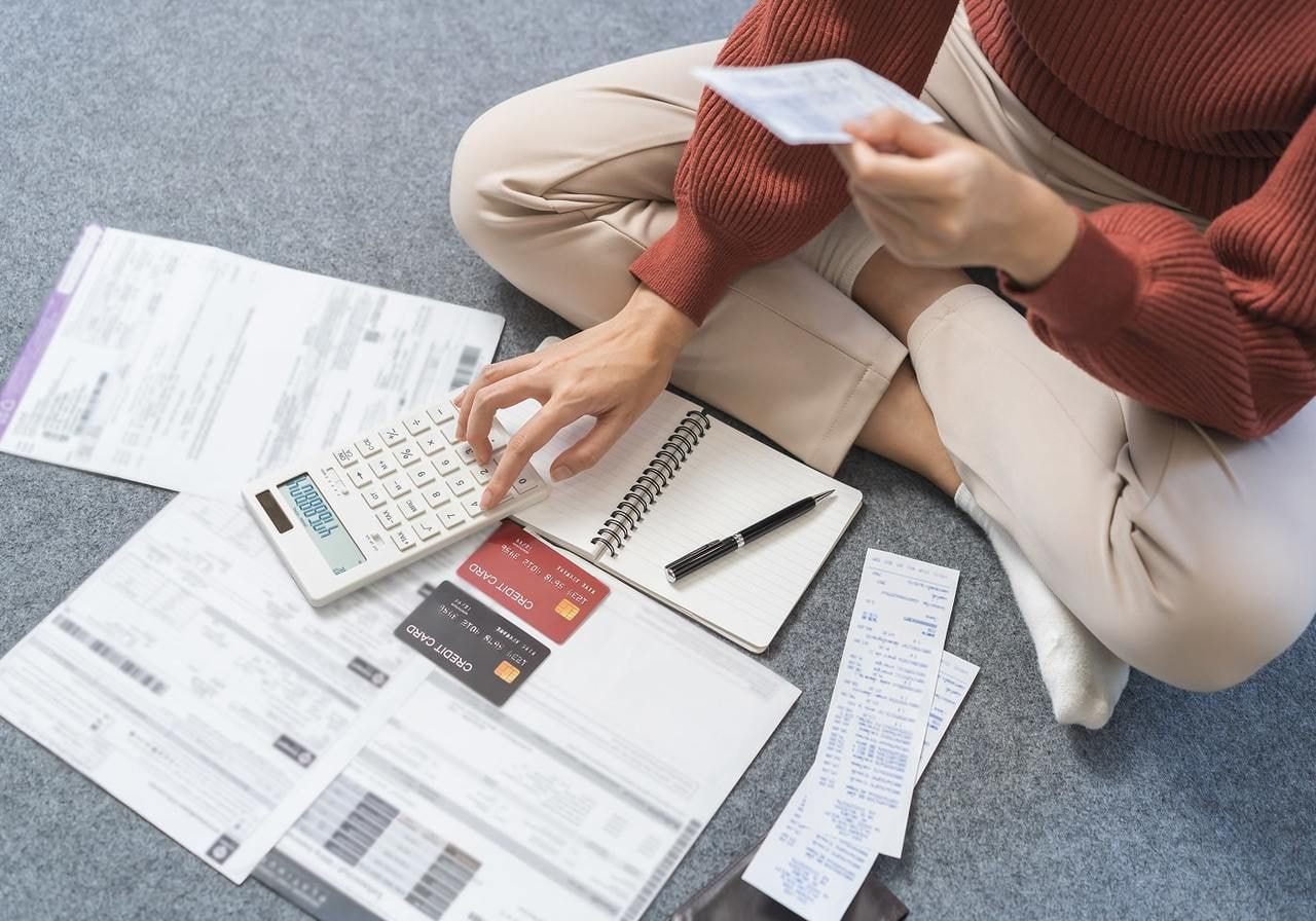 A person sitting on the floor and counting expenses.